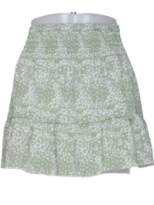 Grön blommig kjol från Gina Tricot - Supersöt grön kortkjol från Gina Tricot med vitt blommönster och volangdetalj. Kjolen har smock i midjan för en bekväm passform och är perfekt för varma dagar. Lätt och luftig känsla.