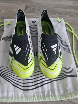 Adidas Predator fotbollsskor svart/vit/gul - Säljer ett par Adidas Predator fotbollsskor i svart, vitt och neon-gult. Skorna har en strömlinjeformad design utan snörning, med mönstrad ovandel och greppvänlig sula för bästa kontroll på planen. Perfekta för dig som vill sticka ut och dominera matchen. Använd fåtal gånger och dem är typ nya. Box och pås inkluderar✅ går alltid att diskutera. 