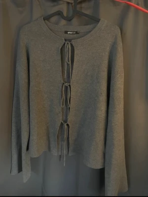 Kofta med knytning  - Grå kofta från Gina Tricot med knyt framtill. Modellen är långärmad med lite vida ärmar. Jätte fin stickad kofta och perfekt till hösten. Helt slutsåld, säljs för att den inte kommer till användning. Kontakta för egna bilder.