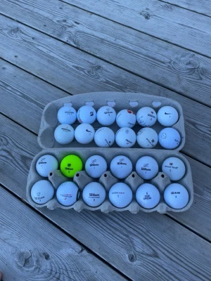 Bland golfbollar  - Säljer ett bland paket med 24 golfbollar, mestadels vita men en är gul. Flera olika märken syns, bland annat Wilson och Nike. Perfekt för dig som vill fylla på golfbolls-förrådet snabbt och smidigt. Bollarna är i skick b a 