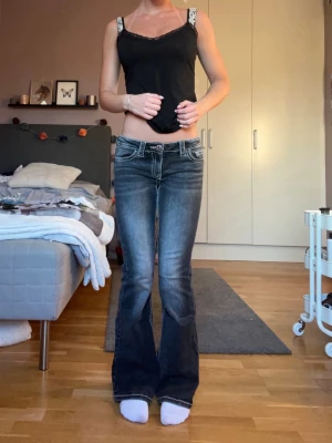 Bootcut jeans  - Säljer ett par mörkblå bootcut jeans med tydliga kontrastsömmar och slitningar framtill. Jeansen har låg midja, klassiska fem fickor och markerade bakfickor med dekorativa sömmar. Perfekta för en avslappnad och trendig look. Stl 158, men passar xs. 