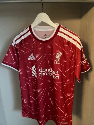 Liverpool Fotbollströja 26/27 - Helt ny och trendig Liverpool 2026 / 2027 säsongs Hemma version fotbollströja. Nypris runt 1099kr. Passformen på tröjan är som en oversized t-shirt i storlek S. Tröjan kommer med original förpackning och skickas i förstärkt påse för att hindra skador eller slit under frakt. Kontakta vid funderingar, och kolla min profil om du vill se andra tröjor. 
