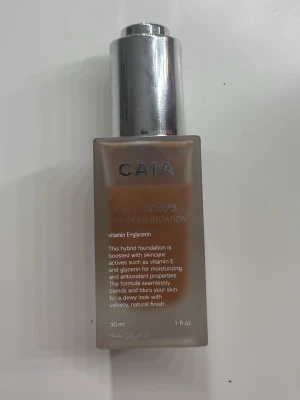 CAIA Dewy Drops Serum Foundation 50W - Foundation från CAIA i nyansen 50W. Dewy Drops Serum Foundation ger en återfuktande och naturlig finish med ingredienser som vitamin E och glycerin. Kommer i en fyrkantig glasflaska med pump och silverfärgat lock. Innehåller 30 ml. Använt bara några fåtal gånger. 