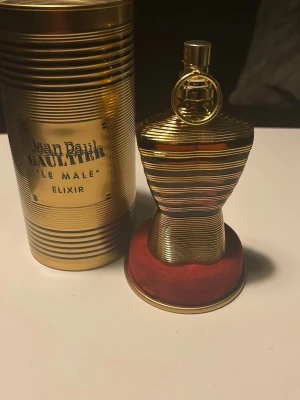 Jean Paul Gaultier Le Male Elixir - Exklusiv parfymflaska från Jean Paul Gaultier, Le Male Elixir. Flaskan har en unik kroppsliknande form i guld med horisontella ränder och kommer med en matchande guldfärgad metalltub. Perfekt för dig som vill ha en lyxig och iögonfallande doft på hyllan.