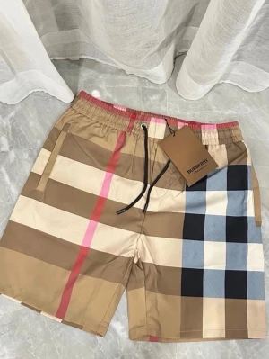 Rutig Burberry shorts med snörning - Snygga shorts från Burberry med klassiskt rutigt mönster i beige, svart, vitt, blått och rött. Shortsen har elastisk midja med snörning och sidofickor. Perfekta för en trendig och avslappnad stil.