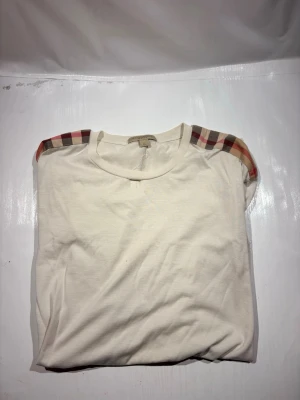 Burberry T-shirt  - Hej! Säljer nu min T-shirtfrån märket Burberry , storlek XL bra skick utöver hål, allt på bilden ingår. Tveka inte på att höra av dig om du har frågor eller funderingar kring kavajen!