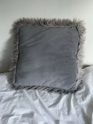 Grå fluffig kudde 45x45 - Säljer en prydnadskudde som fungerar att använda på båda olika håll, som ger olika resultat. 45x45cm