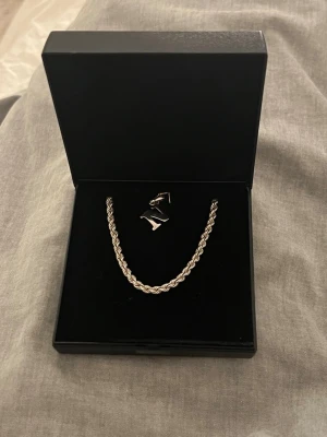 Silverfärgat halsband från Rebecca Falck - Säljer ett stilrent halsband från Rebecca Falck i silverfärg. Halsbandet har en kordell kedja och levereras i original ask. Perfekt för dig som gillar minimalistisk och modern design.