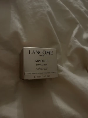 Lancôme Absolue Longevity 15 ml - Lancôme Absolue Longevity är en exklusiv ansiktskräm i en elegant, guldfärgad fyrkantig förpackning. Krämen är framtagen för att ge huden näring och lyster och innehåller 15 ml. Perfekt för dig som vill ha en lyxig hudvårdsrutin.