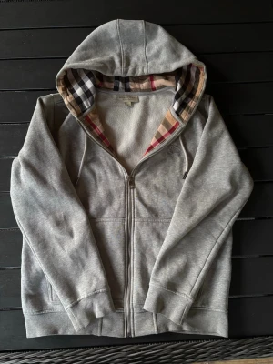 Burberry hoodie - Säljer en snygg grå hoodie från Burberry! Hoodien är i mycket bra skick och har inga defekter. Knappt använd. Om ni har några frågor så är de bara att höra av er😊