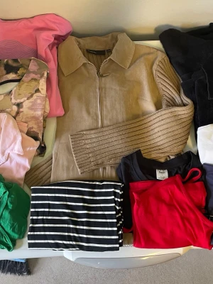 Klädpaket dam/tjej L och 42-44 - 11 plagg Stilren beige jacka med dragkedja framtill och bred krage. En mjuk kjol, flera långärmade plagg en luvtröja.