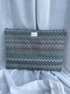 Mönstrad textilväska från Emelo - Snygg datorväska från Emelo med zigzag-mönster i grönt, blått, grått och beige. Väskan har en mjuk textil utsida och stängs med dragkedja upptill. Perfekt för att bära din laptop på ett stilrent sätt. Passar laptop med maxmått 32x24cm.