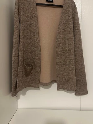Brunmelerad långärmad tröja - En enkel och stilren brunmelerad långärmad tröja med rund hals. Tröjan har en rak passform och är tillverkad i ett mjukt, tunt material som känns skönt mot huden. Perfekt att matcha med jeans eller kjol.
