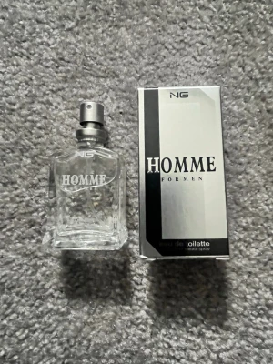 Homme For Men parfym 15ml - Fräsch parfym från NG med namnet Homme For Men. Flaskan är genomskinlig med silverfärgad spray och har en stilren, kantig design. Förpackningen är svart och silver med tydlig logga. Perfekt för dig som gillar maskulina dofter.