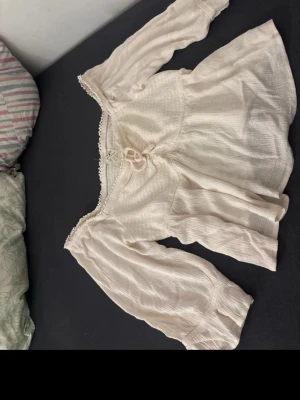 Vit boho-blus från Self Esteem - Söt vit blus från Self Esteem i boho-stil med långärmade puffärmar, knytning framtill och spetsdetaljer vid halsringningen. Tillverkad i ett lätt, krinklat tyg som ger en avslappnad och trendig look. Tröjan i i storlek lx men jag skulle säga att den passar m och l också