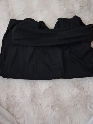 Svarta leggings i polyester och elastan - Ett par svarta leggings i storlek S, tillverkade av 95% polyester och 5% elastan. De har en mjuk och stretchig känsla som gör dem riktigt bekväma och perfekta för en avslappnad look. Midjan är elastisk för extra komfort.