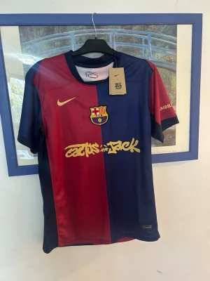 FC Barcelona matchtröja Lamine Yamal - Säljer en officiell FC Barcelona matchtröja från Nike i rött och marinblått med klubbmärke och gul logga på bröstet. På ryggen står Lamine Yamal och nummer 19 i gult. Tröjan har korta ärmar och är tillverkad i ett lätt, ventilerande material.