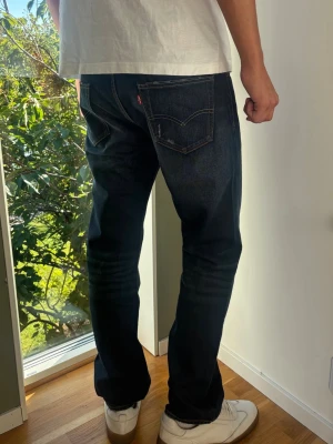 Authentic Levi's 504 W33 L32 Herrjeans Rak Passform  - Autentiska dark blue Levi's 504 jeans (W33/L32), skick A (som nya). Snygg tvätt med snygga detaljer, diskreta slitningar från fabrik  och brun insida . Perfekt rak passform.  Mått [platt]: (Jämför med en jeans som du gillar) A: Midja: 43,5 cm B: Längd: 106 cm C: Lår: 27 cm D: Benslut: 21 cm Lite för korta på modellen på bilden som är 189 cm lång, han har fått dra ner byxorna lite.  Tveka inte att höra av dig vid frågor eller funderingar. Skickas snabbt! 