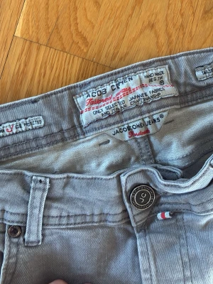 Ljusblå jeans från Jacob Cohen - Snygga ljusblå jeans från Jacob Cohen med smal passform och klassisk femficksdesign. Tillverkade av mjukt japanskt tyg och har diskreta detaljer som knapp med logga och liten trikolor-flagga vid fickan. Perfekta för en avslappnad men stilren look. Har lappen på hur mycket jag köpte dem för men skickar privat 