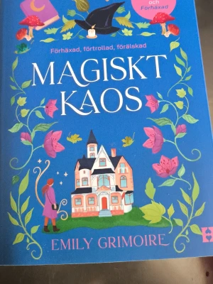 Magiskt Kaos av Emily Grimoire - En färgstark skönlitterär bok med blått omslag, magiska illustrationer som trollstav, svamp, blommor och ett sagoslott. Titeln 'Magiskt Kaos' och författaren Emily Grimoire syns tydligt. Perfekt för dig som gillar magi och romantik.