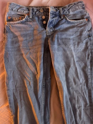 Ljusblå jeans  - Ett par vanliga ljusblåa raka jeans med flera knappar fram. Välanvända men i bra skick!