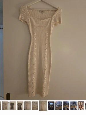 Vit ribbad stickad klänning från Guess - Snygg vit ribbad klänning med korta ärmar och v-ringad hals. Klänningen är midilång och har fina stickade detaljer längs framsidan. Perfekt för dig som gillar en enkel men ändå elegant look.