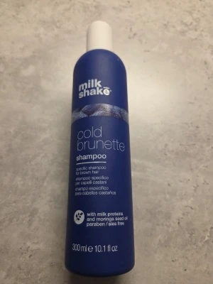 Milk Shake Cold Brunette Shampoo - Säljer ett Milk Shake Cold Brunette Shampoo, perfekt för brunt hår. Kommer i en blå flaska på 300 ml och innehåller mjölkproteiner och moringaolja. Fri från parabener och sulfater. Ger en kall ton till brunt hår. Använt halva cirka. 