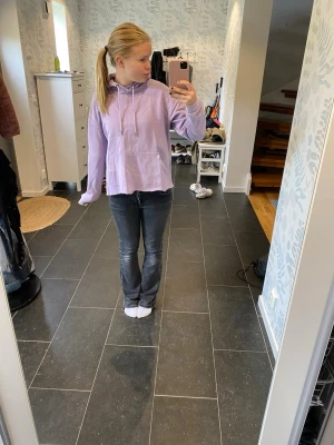 Ljuslila hoodie med huva - Säljer en ljuslila hoodie med huva och dragsnören. Hoodien har en stor magficka och ribbade muddar vid ärmsluten. Passar perfekt för en avslappnad och chill stil. Materialet ser ut att vara mjukt och bekvämt, troligen bomullsblandning. Jag har klippt av den vilket gör att man inte kan ha något i fickan. 