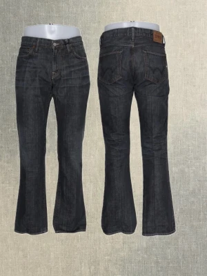 Edwin bootcut slim jeans - Edwin slim bootcut jeans i snygg och tidlös modell. Sitter slim över låren och går sedan lätt ut nertill, vilket ger en snygg bootcut-passform. Perfekta att matcha med sneakers, boots eller loafers.   Storlek: W33 L32  Färg: mörk denim  Midja: 43cm  Innerbenslängd: 81cm 