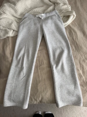 Ljusgrå mjukisbyxor med raka ben - Säljer ett par ljusgrå mjukisbyxor med raka ben och dragsko i midjan. Byxorna har fickor på sidorna och är gjorda i ett mjukt, bekvämt material som passar perfekt för chill dagar. Klassisk och enkel design som är lätt att matcha. Fläckar(se bild) vet ej om det går bort i tvätten då jag ej provat 