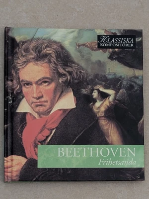 Beethoven Frihetsanda CD - En CD med hård pärm ur serien Klassiska Kompositörer, med titeln 'Beethoven Frihetsanda'. Omslaget har ett porträtt av Beethoven i färgstarka toner och klassisk målning i bakgrunden. CD fodralet innehåller information om Beethovens verk.