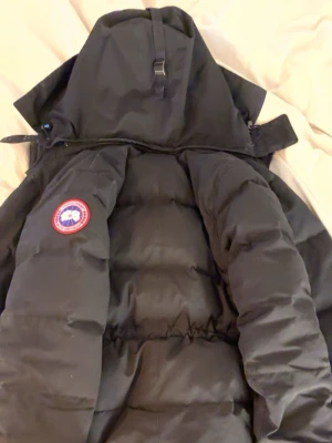 Chelsea parka Canada goose Dam - Säljer en svart dunjacka från Canada Goose med huva och klassisk logotyp på ärmen. Jackan har en puffig design, dragsko i midjan som man kan spänna ut och in i en bra passform och flera praktiska fickor. Perfekt för kalla vinterdagar och riktigt varm tack vare dunfyllningen.💕Storlek M men passar även för dem som bruka ha S som mig☺️pris kan diskuteras!!