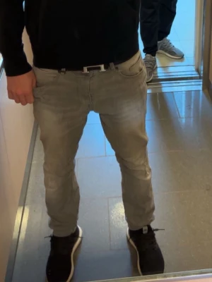 Grå slim fit jeans - Snygga grå slim fit jeans med klassisk femficksdesign och dragkedjegylf. Jeansen har en något tvättad look och sitter tajt längs benen för en modern stil. Perfekta till sneakers och hoodie för en avslappnad vibe.