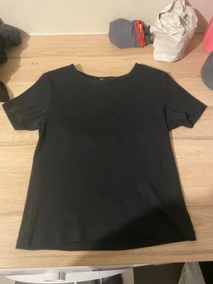 Svart ribbad t-shirt - En stilren svart t-shirt med ribbad struktur och korta ärmar. Modellen har en klassisk rund halsringning och en rak passform som funkar till det mesta. Perfekt basplagg i garderoben för en enkel och clean look.