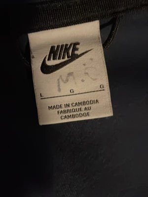 Blå Nike hoodie med dragkedja - Snygg blå hoodie från Nike med dragkedja framtill och klassisk Nike-logga på bröstet. Hoodien har huva och en randig detalj över bröstet. Perfekt för en sportig och avslappnad stil.
