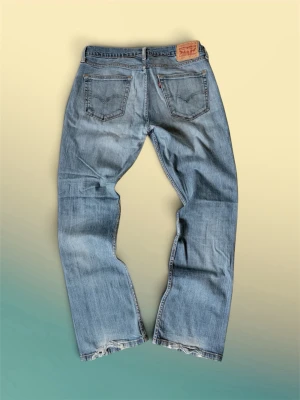 Levis 527  - Säljer ett par ljusblå Levis 527 W33-L32 med raka ben och flera slitningar och hål på framsidan för en riktigt avslappnad och trendig look. Jeansen har klassisk femficksdesign och är gjorda i denim. Perfekta för dig som gillar en edgy stil.