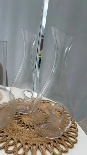 Två eleganta karaffer i glas - Säljer två stilrena karaffer i klart glas med unik form och rund öppning i botten. Perfekta för att servera vin eller vatten vid middagsbordet. Modern design som passar in i de flesta hem och ger en lyxig känsla till dukningen.