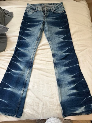 Blå utsvängda jeans från Weekday - Säljer ett par blå jeans från Weekday med coolt blekt mönster och utsvängda ben. Klassisk femficksmodell med knappgylf och kontrastsömmar. Använda 1-2 gånger. SKITCOOLA!!!