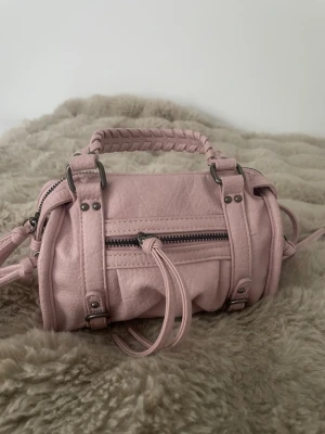Bershka handväska rosa  - Säljer en rosa superfin handväska från Bershka. Säljer då den inte kommer till användning🥰 Använd 2 gånger. Ett axelband tillkommer också ifall du hellre skulle vilja ha den runt axeln. Jättefin och bra skick! Pris kan diskuteras❤️