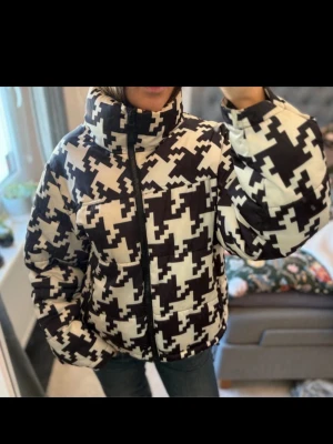 Svartvit pufferjacka med pixelmönster - Säljer en riktigt snygg pufferjacka i svart och vitt med ett unikt pixelinspirerat mönster. Jackan har hög krage, dragkedja framtill och två sidofickor. Perfekt för dig som vill sticka ut i vinterkylan och gillar streetwear-vibbar.