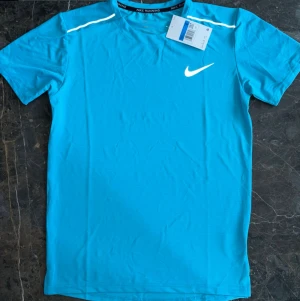 Nike Miller blå ser t-shirt & shorts - Helt nytt oanvänd med etikerna kvar. Nike Miller set i färgen ljusblå, Båda plaggen har Nike-logga i vitt som är reflex och glänser vid ljus/flash. Storlek M. Kan säljas billigare vid snabb affär tveka inte och skriva om fler bilder eller funderingar.