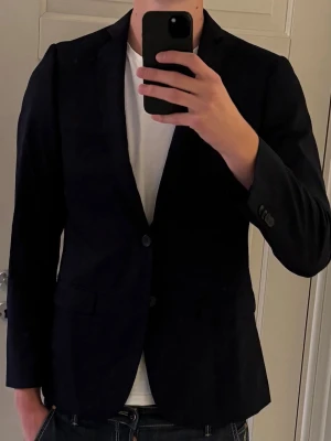 Kavaj  - Mycket elegant kavaj från Thomas Goodwin i storlek 48! I snygg mörkblå färg och detaljerna invändigt i röd färg. En sofistikerad kavaj! 