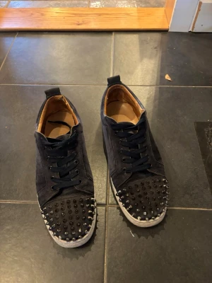 Mörkblå louboutins med bitar - Säljer ett par snygga Mörblå med nitar skorna har tecken på användning vissa nitar har tappat lite färg och insidan av skon är också lite sliten inget som syns med skon på eller som känns när man går, mockan är fortfarande i bra skick och sulan går att tvättas upp, för fler frågor är det bara att skriva 🙌 det som ingår: box, extra nit och extra snören, samt ett par till sulor men dom är lite mer slitna.