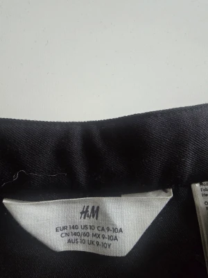 Svart plisserad kjol från H&M - Snygg svart plisserad kjol från H&M med bred linning och klassisk kort modell. Kjolen har en enkel och stilren look som passar till många olika outfits. Perfekt för dig som gillar en tidlös och trendig stil. Använd 2 gånger