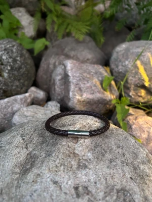 Brunt flätat läderarmband - Snyggt armband i mörkbrunt flätat läder med ett stilrent magnetlås i silverfärgad metall. Perfekt accessoar för dig som gillar en enkel men trendig look. Passar både killar och tjejer och är lätt att matcha med andra smycken.