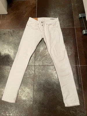 Vita skinny jeans med låg midja - Säljer ett par vita skinny jeans med låg midja och klassisk femficksmodell. Jeansen har smal passform hela vägen ner och är tillverkade i ett stretchigt material för extra komfort. Perfekta att matcha med en oversized hoodie eller crop top.