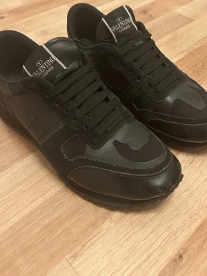 Svarta Valentino rockrunners - Säljer dessa valentino rockrunners i hel svart för att man har börjat tröttna på de nu lite. Storlek 40. Funkar hur bra som helst. Helt perfekt inför alla säsonger skulle jag säga. De har olika detaljer på skon som mockan, lädret, spikarna och massa fler. Kartongen och kortet på sista bilden ingår. Skriv om ni är intresserade. 