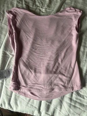 Ljusrosa ärmlös topp från Gina Tricot - Säljer en enkel och stilren ljusrosa topp från Gina Tricot. Toppen är ärmlös med rund halsringning och har en mjuk, stretchig känsla. Perfekt att matcha med jeans eller kjol för en fräsch look. Nåhot liten i storlek. 