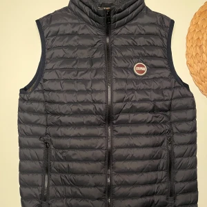 Mörkblå dunväst från Colmar - Snygg mörkblå dunväst från Colmar med dragkedja. Västen har en stilren design med Colmar-logga på bröstet och praktiska fickor med dragkedja. En snygg väst som funkar till allt helt enkelt. Strl xs men funkar säkert som S 