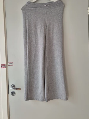 Grå vida mjukisbyxor - Säljer ett par grå mjukisbyxor med breda ben  Byxorna är tillverkade i mjukt och stretchigt material, perfekta för chill dagar. Enkel och stilren design utan synliga loggor eller detaljer. Inköpta på Lager 157. Lappen avklippt.  Storlek S